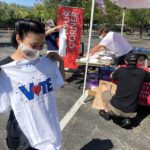 Rhenan Miravalles of Larkspur looks over her new vote t-shirt while her partner Vaughn Wooster registers to vote before a march and car caravan at the Northgate Mall in San Rafael, Calif. on Saturday, July 4, 2020. (Sherry LaVars/Marin Independent Journal)